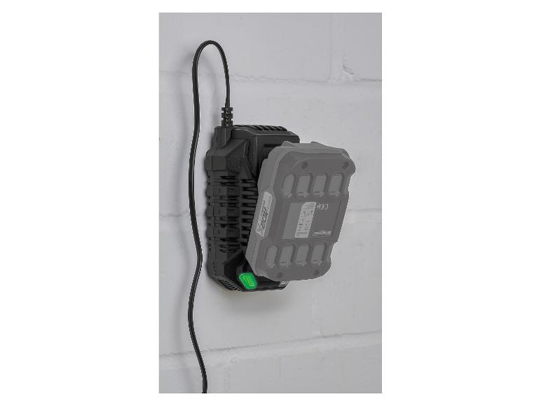 Czarna ładowarka z podłączoną szarą baterią, zamontowana na białej ścianie z cegieł.