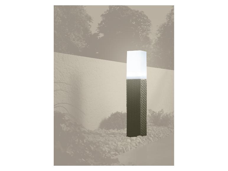 Lampa ogrodowa z plecioną podstawą i białym kloszem, otoczona kamykami.