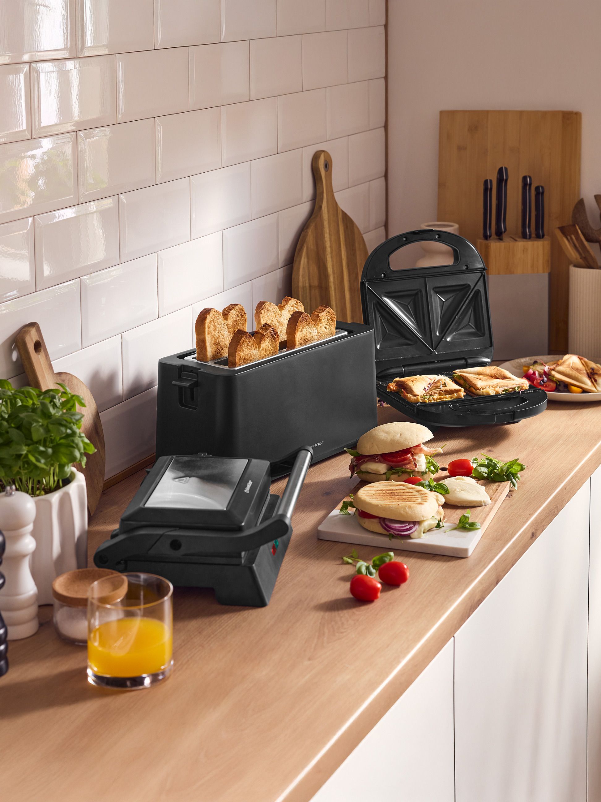 Blat kuchenny z tosterem, opiekaczem do kanapek i grillem, przygotowanymi kanapkami i sokiem.