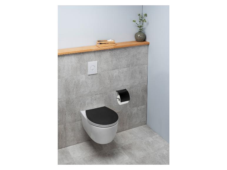 Toaleta z czarną deską sedesową, podwieszanym systemem spłukiwania i czarną podpórką na papier toaletowy.