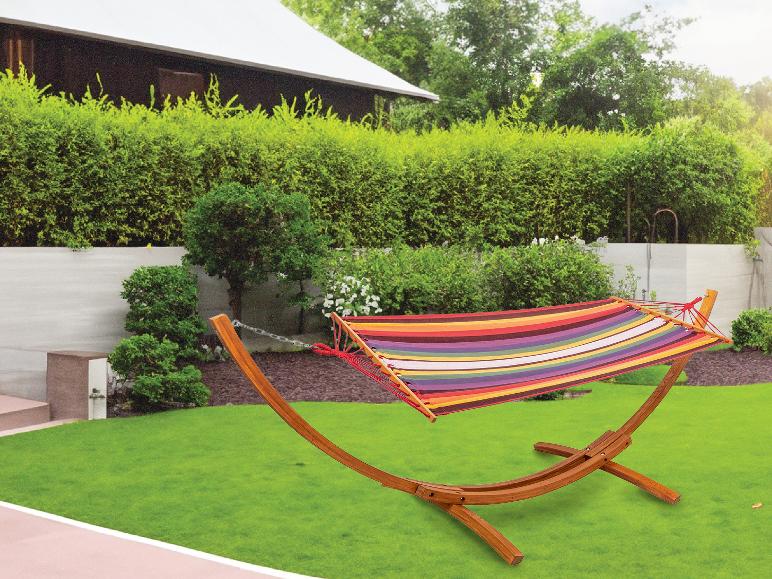 Kolorowa hamaka na drewnianym stojaku w ogrodzie.