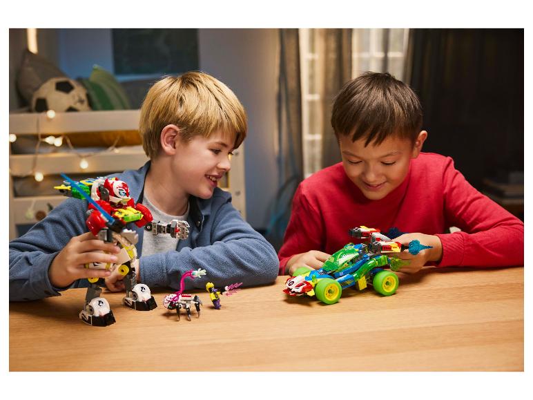 Dwóch chłopców bawi się zestawami LEGO, robotem i samochodem wyścigowym, przy drewnianym stole.