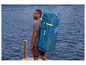 Mężczyzna niesie na plecach dmuchany paddleboard Hydro-Force.