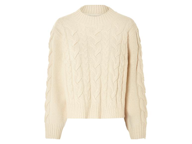 Beżowy sweter z warkoczami.