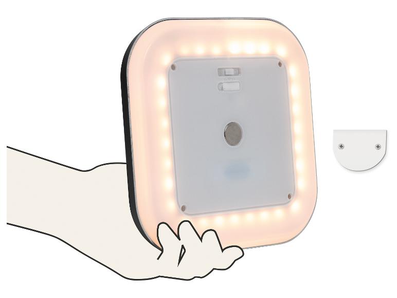 Kwadratowa lampa LED z ciepłym białym światłem, trzymana w dłoni, z uchwytem montażowym obok.