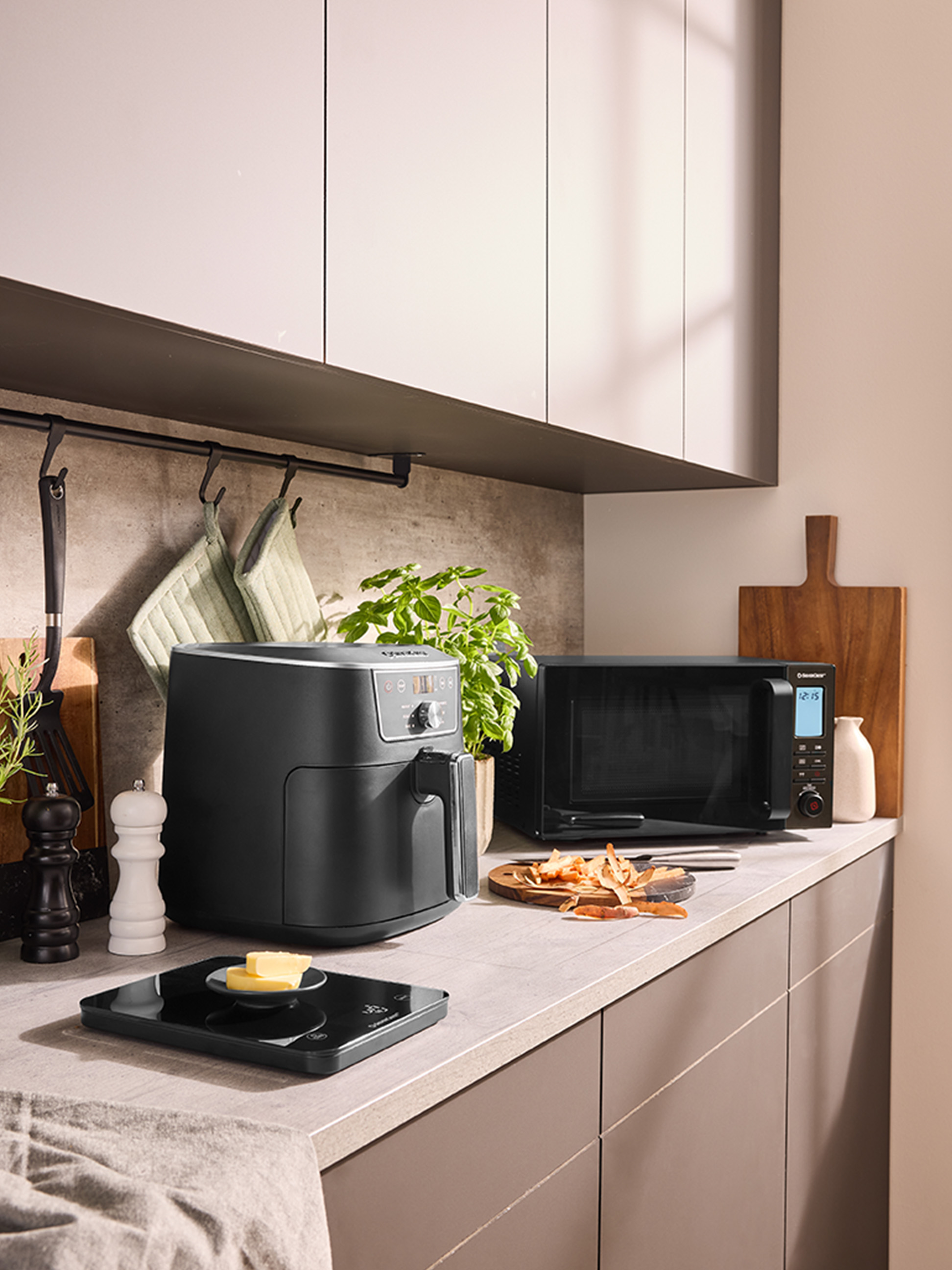 Frytkownica beztłuszczowa i kuchenka mikrofalowa na nowoczesnym blacie kuchennym.