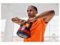 Mężczyzna w pomarańczowej koszulce trzyma 10-kilogramową kettlebell.