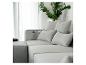 Szara modułowa sofa z poduszkami i zieloną rośliną w srebrnym wazonie.