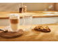 Latte w szklance o podwójnych ściankach i biscotti na drewnianym stole.