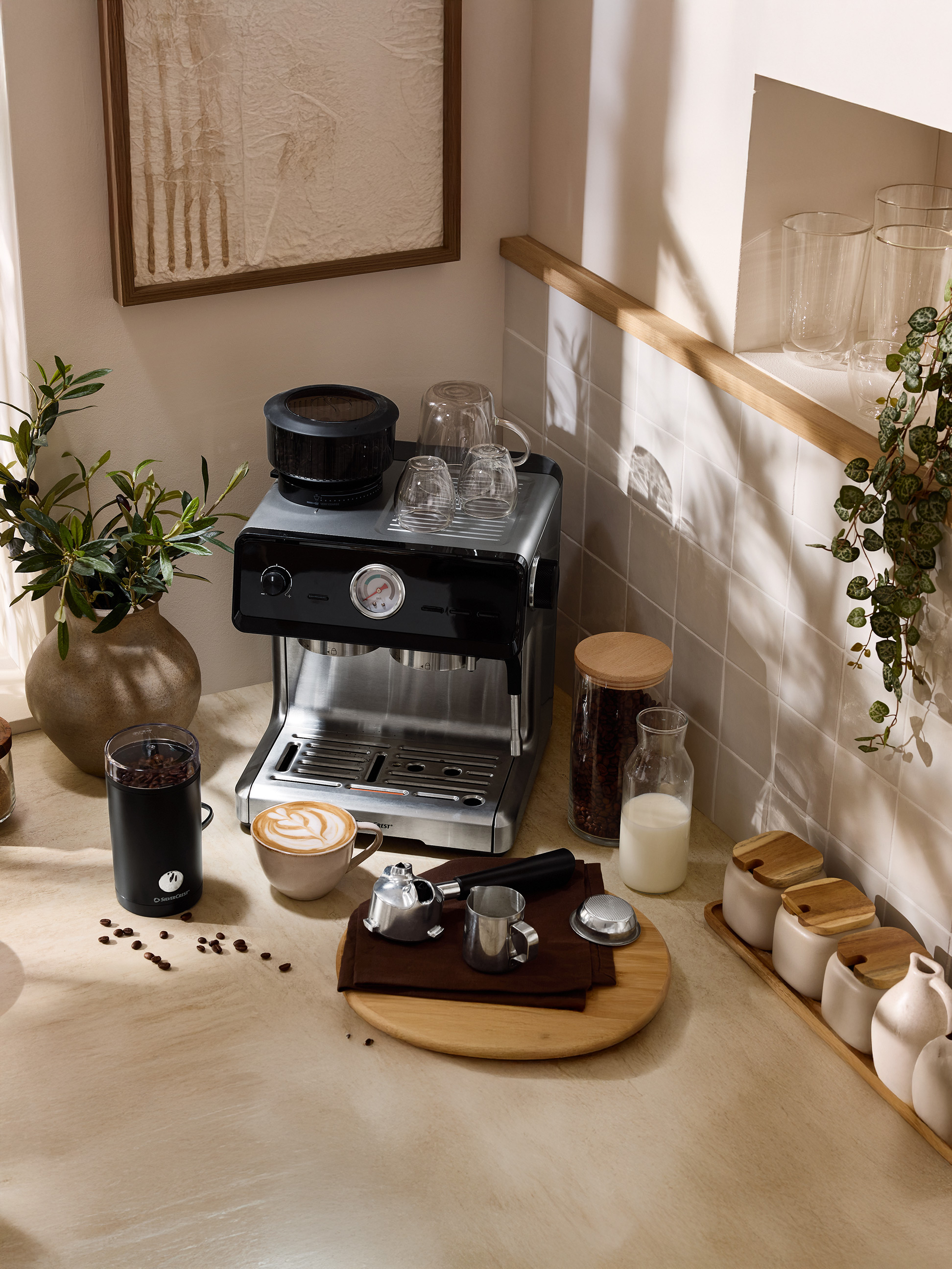 Ekspres do kawy z młynkiem, filiżanką kawy latte i akcesoriami na blacie kuchennym.