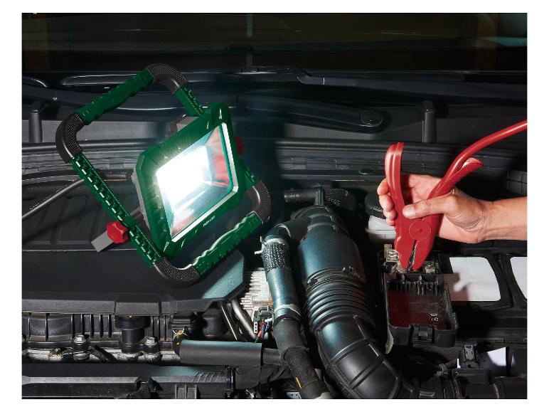 Lampa robocza PARKSIDE oświetlająca silnik samochodu podczas podłączania zacisków akumulatora.