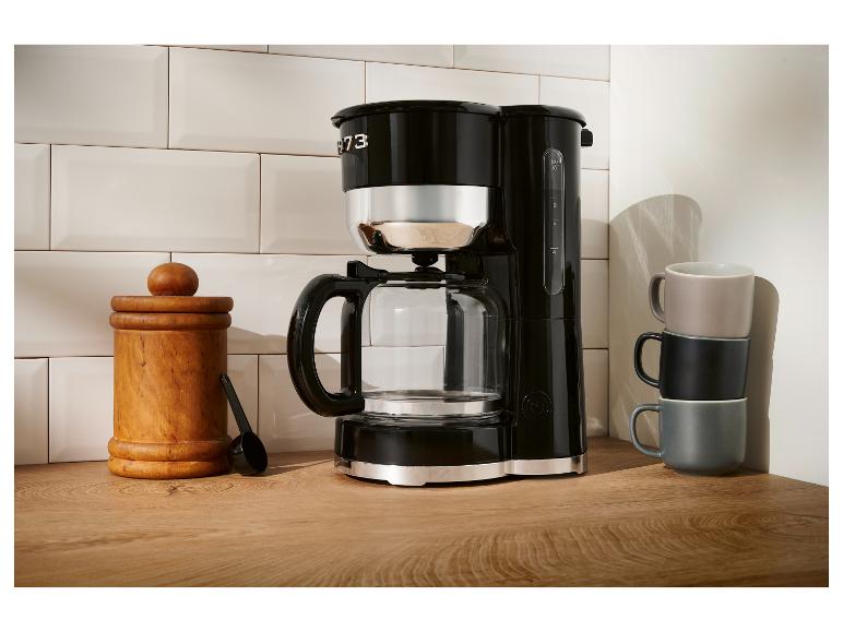 Czarny ekspres do kawy Smeg na drewnianym blacie.