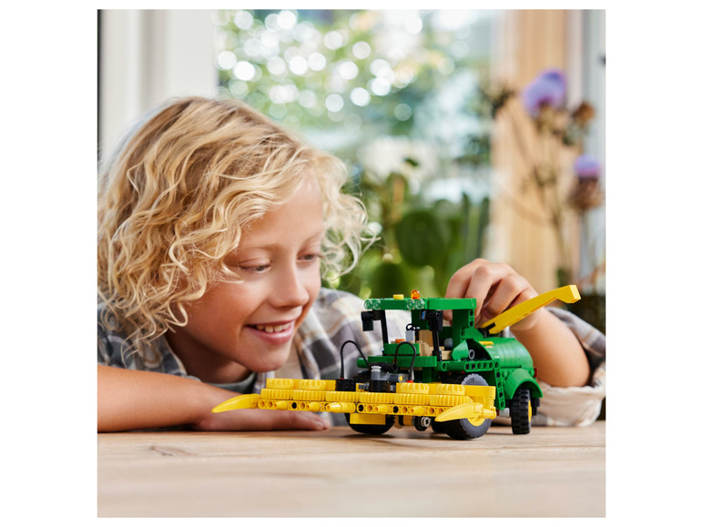 Dziecko bawi się LEGO kombajnem John Deere.