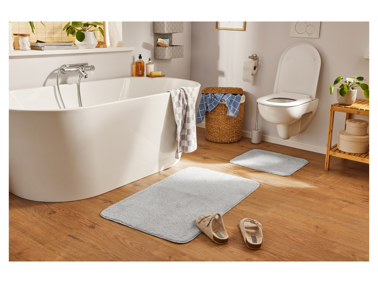 Łazienka z wanną, toaletą i dwiema matami łazienkowymi.