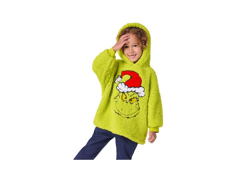 Chłopiec w zielonej bluzie z kapturem Grinch i granatowych spodniach.