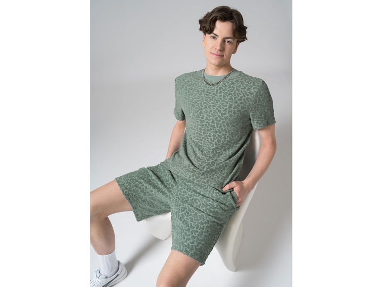 Mężczyzna w zielonej koszulce i szortach w panterkę.