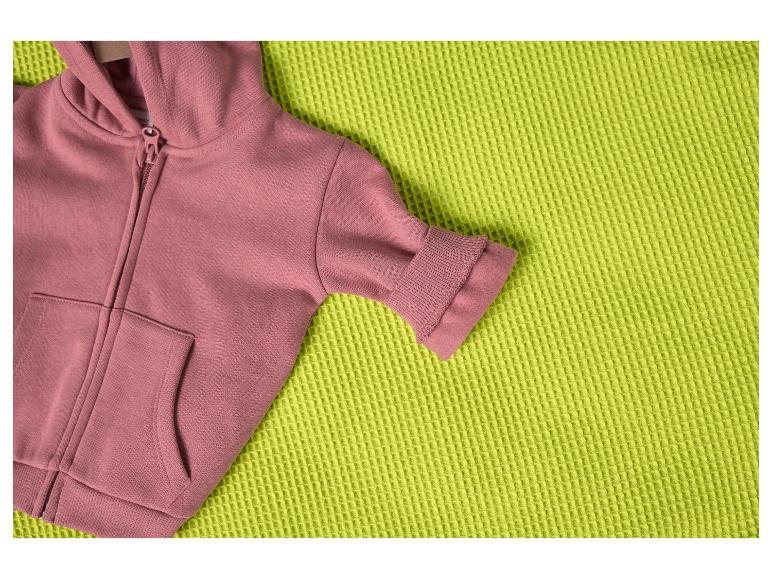 Różowa bluza z kapturem na teksturowanym limonkowym kocu.