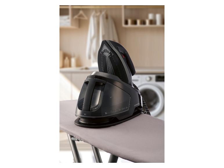 Żelazko parowe na desce do prasowania w pralni.