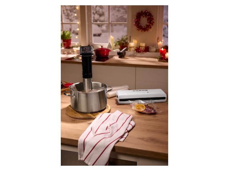 Urządzenie sous vide w garnku, zgrzewarka próżniowa i zapakowana próżniowo żywność na blacie kuchennym.