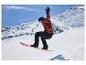 Snowboardzista w czerwono-czarnej kurtce, czarnych spodniach, kasku i goglach, w powietrzu.