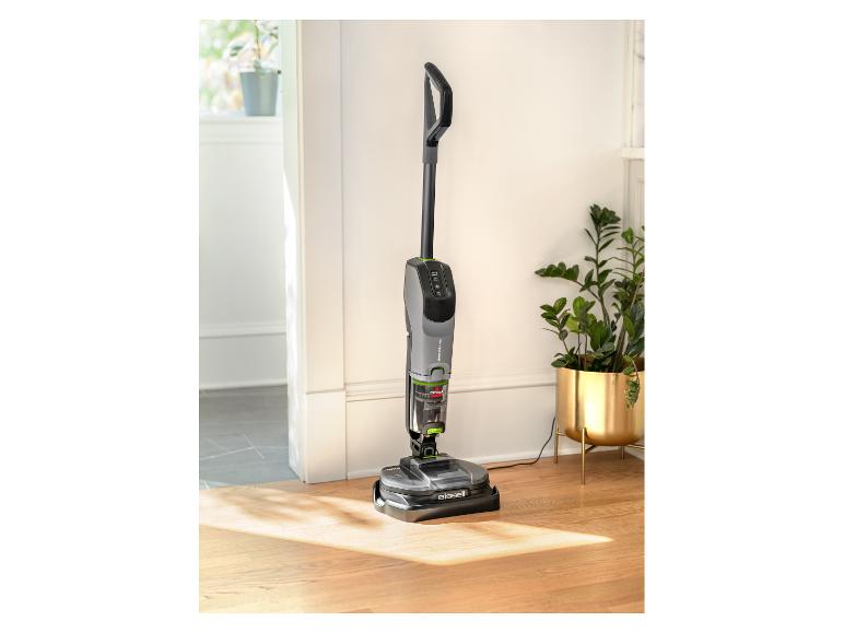 Odkurzacz i mop Bissell SpinWave + Vac na drewnianej podłodze z roślinami w tle.