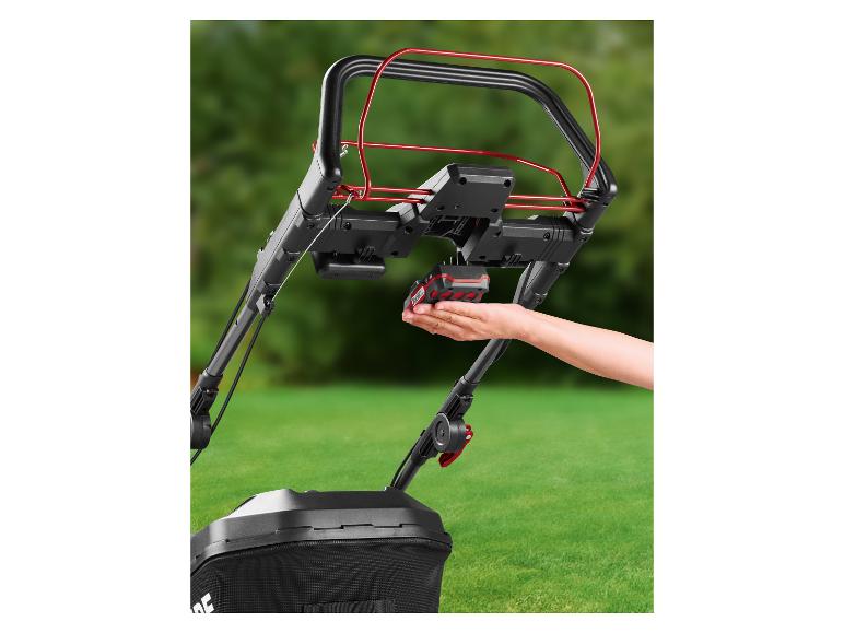 Ręka wkłada baterię do bezprzewodowej kosiarki Parkside.