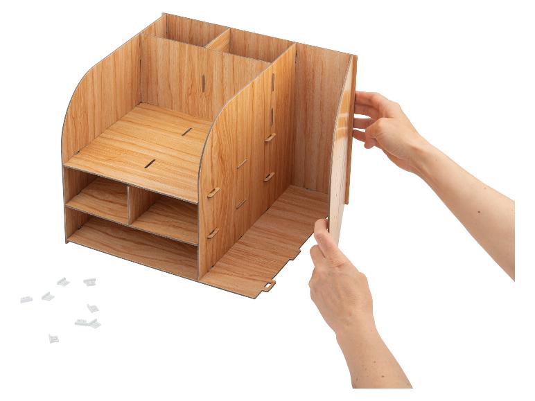 Ręce składające drewniany organizer na biurko z wieloma przegródkami i półkami.