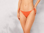 Kobieta w pomarańczowych majtkach bikini.