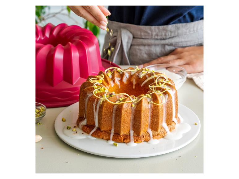 Ciasto bundt polewane lukrem, ozdobione pistacjami i skórką z cytryny.