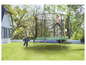 Dziewczynka skacze na trampolinie w ogrodzie.