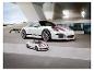 Białe Porsche 911 GT3 i mniejszy model puzzli przed nowoczesnym budynkiem.