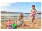 Dwoje dzieci bawi się zabawkami do piasku na plaży, w tle morze i góry.