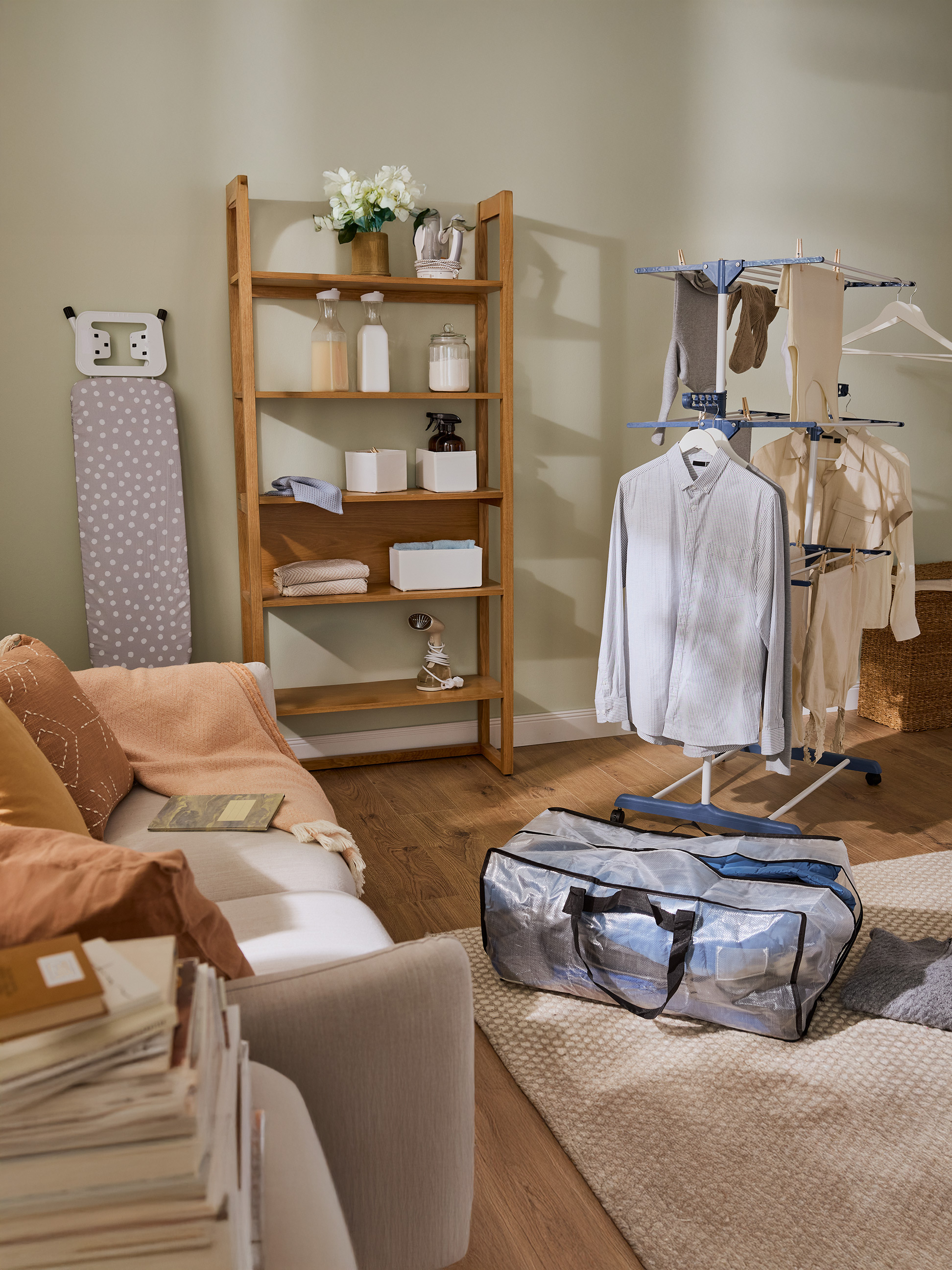 Pralnia z drewnianą półką, deską do prasowania i suszarką na pranie z ubraniami.