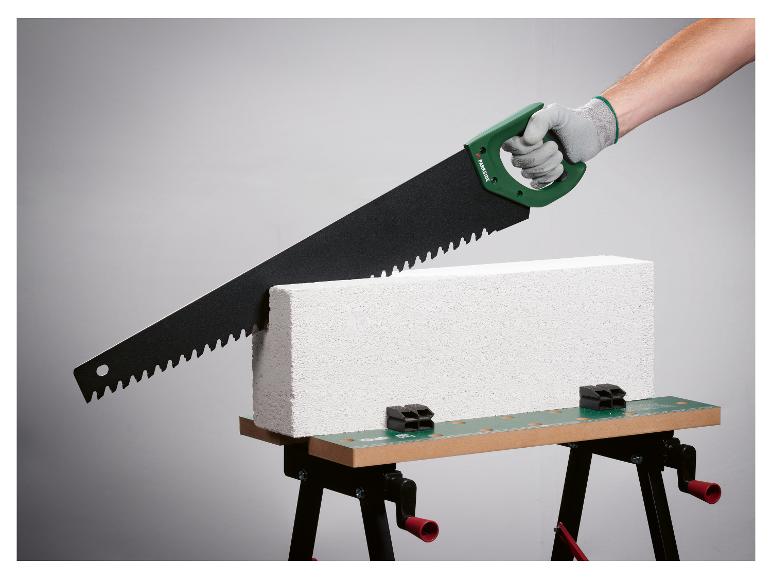 Piła ręczna Parkside tnąca bloczek betonowy na stole warsztatowym.