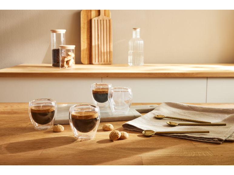 Dwie filiżanki espresso z ciasteczkami na drewnianym stole.
