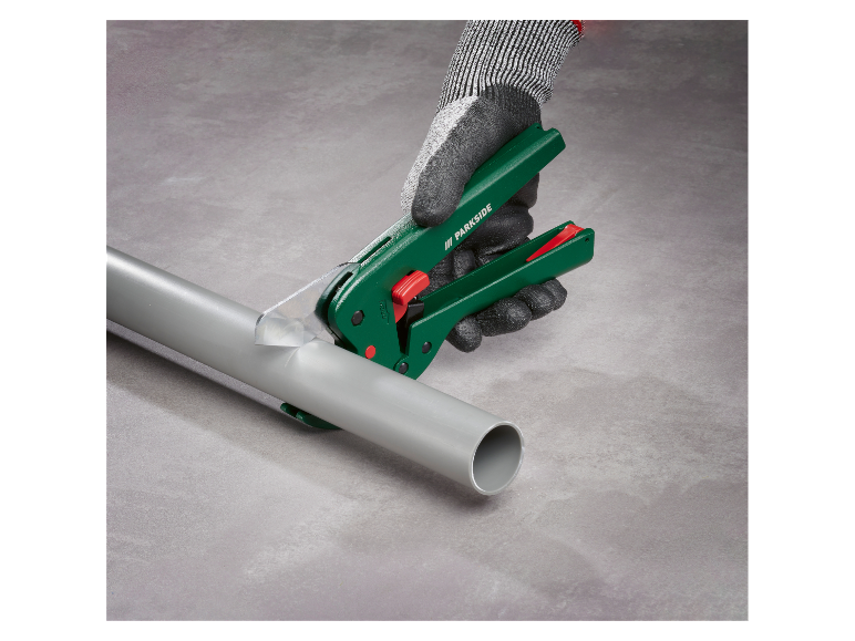 Szare rękawiczki trzymają narzędzie Parkside do cięcia rur PCV.