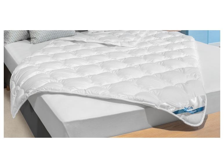 Biała kołdra BeCo z poduszkami na łóżku.