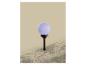 Lampa solarna ogrodowa z fioletową kulą, oświetlająca rabatę.