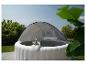 Dmuchane jacuzzi z zadaszeniem, dwoma napojami i zielonym ogrodem w tle.