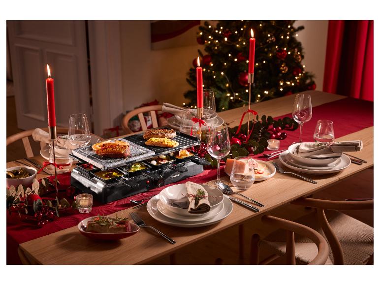 Grill raclette z płytą kamienną i grillową na świątecznym stole z dekoracjami.