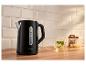 Czarny czajnik na drewnianym blacie z filiżanką herbaty i cytrynami.