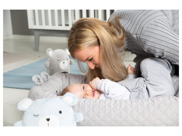 Mama i dziecko w szarym kokonie niemowlęcym z misiami w pokoju dziecięcym.
