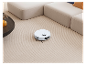 Robot sprzątający na dywanie, obok kanapy.