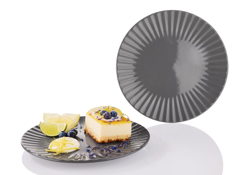 Szary talerz z kawałkiem cytrynowego sernika i plasterkami limonki.