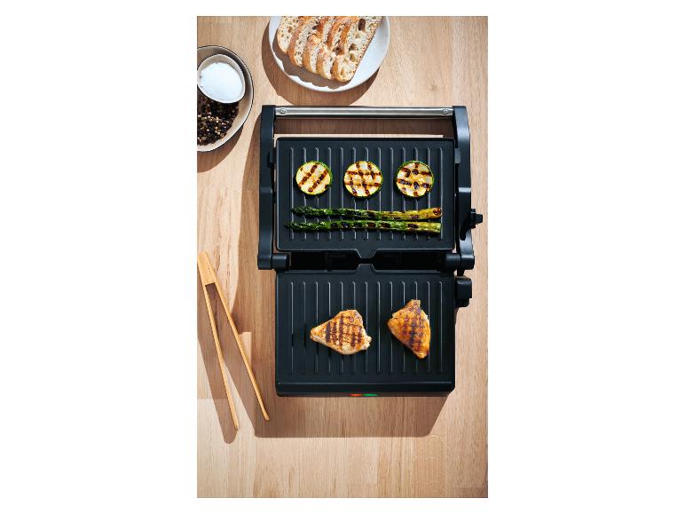 Otwarty grill z grillowanym kurczakiem, cukinią, szparagami i pieczywem na drewnianym stole.