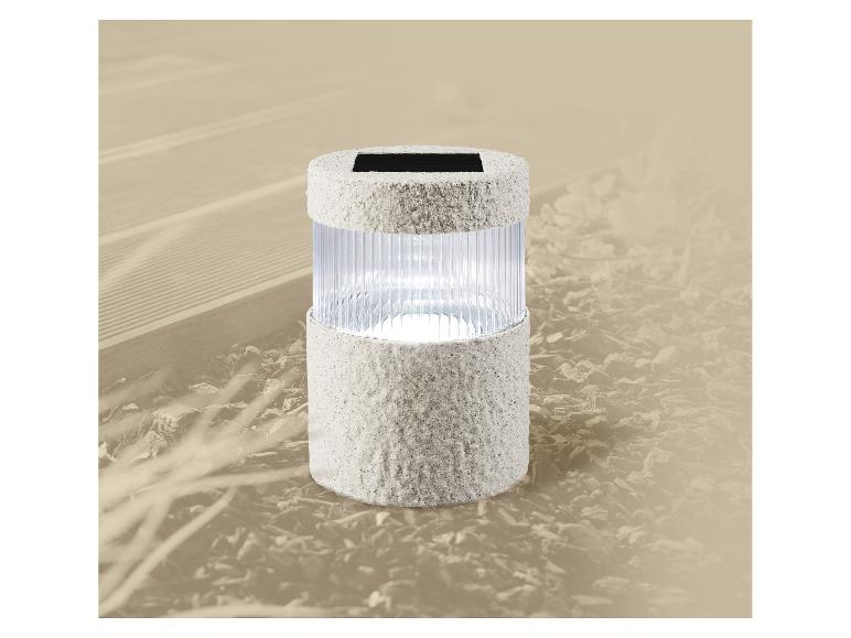 Lampa solarna ogrodowa o teksturowanym szarym wykończeniu, oświetlająca ścieżkę ogrodową.