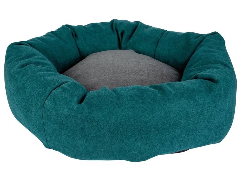 Teal-colored, okrągłe legowisko dla psa z szarą poduszką.