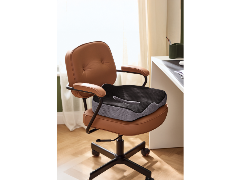 Ergonomiczna poduszka na krzesło biurowe z brązowej skóry w domowym biurze.