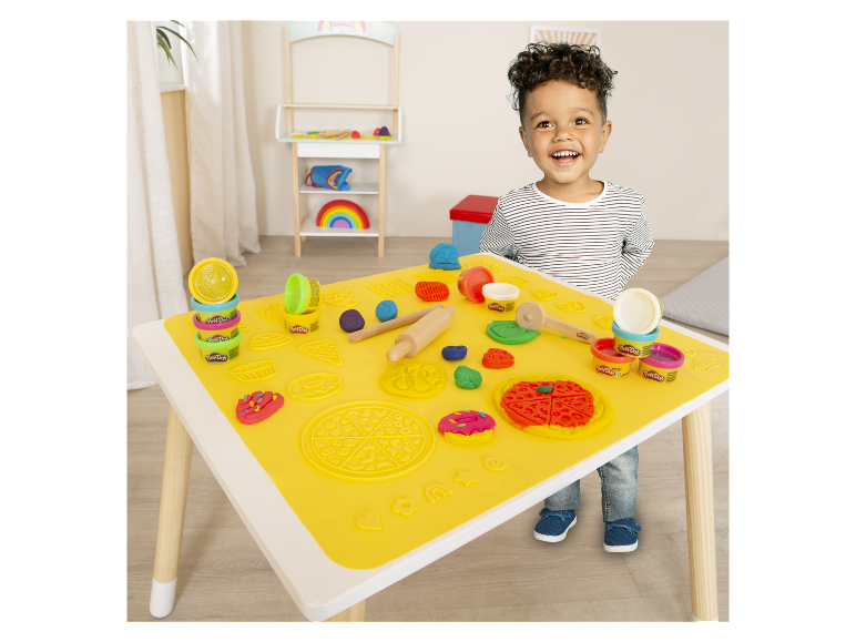 Dziecko bawi się plasteliną Play-Doh przy stole z matą do lepienia.
