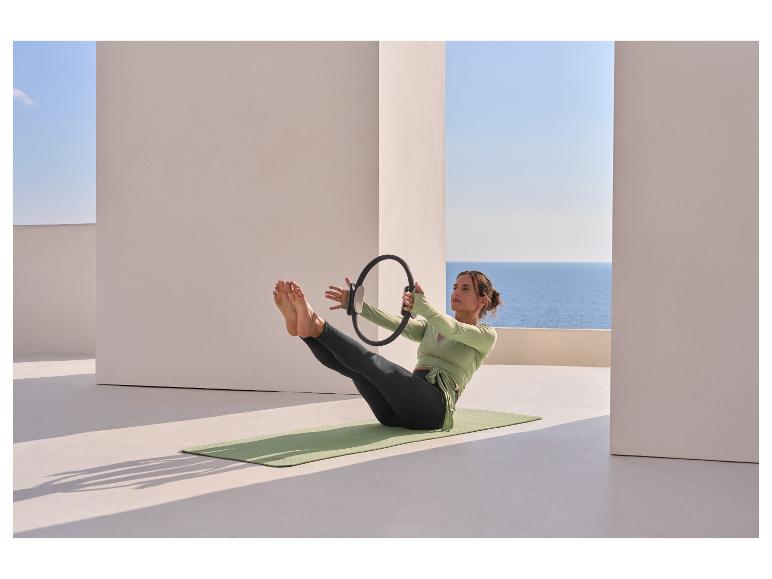 Kobieta w topie funkcyjnym CRIVIT ćwiczy pilates z obręczą na macie.